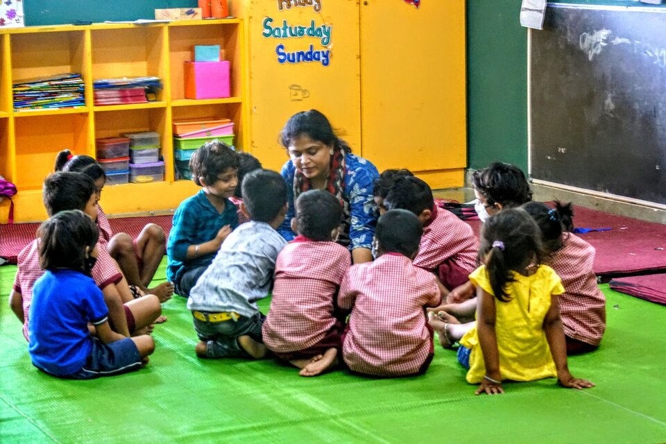 Anganwadi worker and children playing together