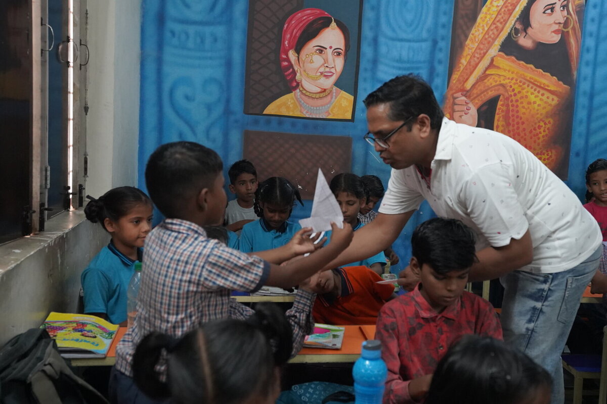 Students showing paper craft to teacher in classroom