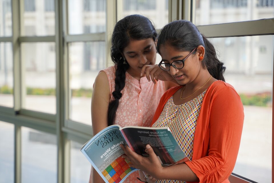 2 students library looking at a magazine